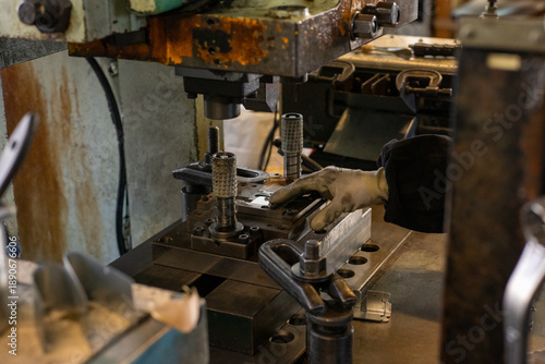 Manual metal press operation with worker hand positioning industrial jig