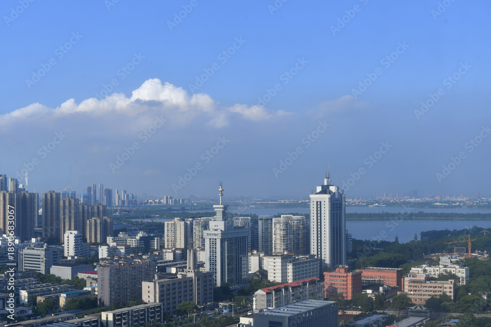 Fototapeta premium Modern Urban Skyline with Waterside Complexes Under Blue Skies