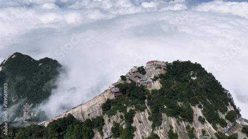 Aerial top-down video of the West Peak and green dragon ridge at Mount Hua, with tourists walking along narrow cliffs above a sea of clouds, Shaanxi province, China