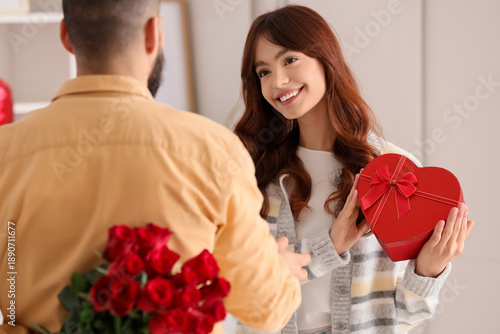 Young man hiding bouquet of...