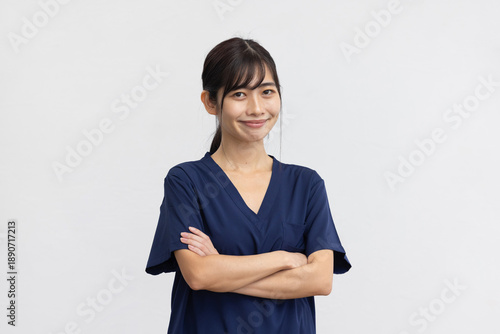 Cuadro en lienzo Confident Young Woman Smiling in Navy Medical Scrubs with Arms Crossed on White