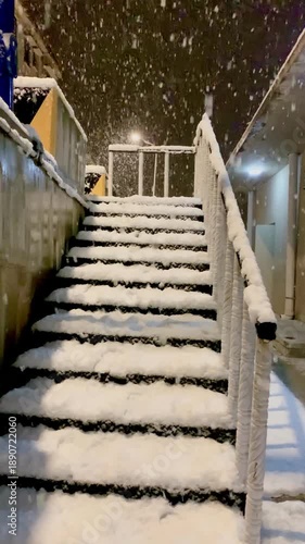 Outdoor stone staircase covered in fresh thick snow during a heavy nighttime snowfall.