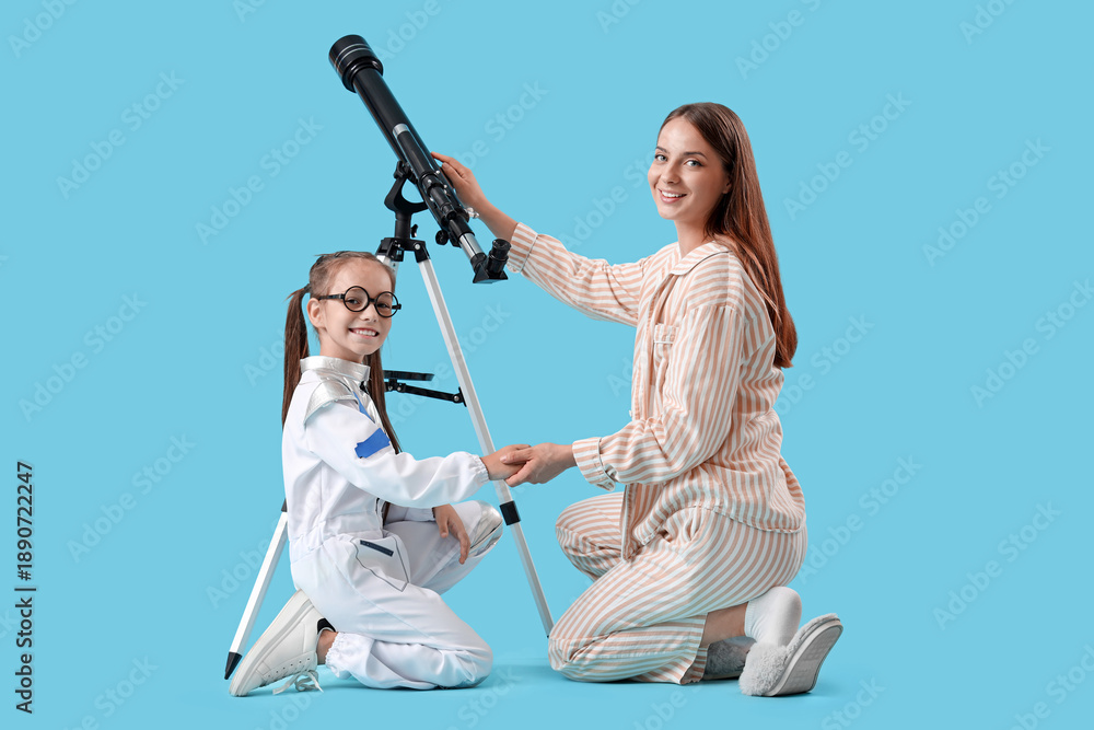 Fototapeta premium Little girl in astronaut costume with her mother and telescope on blue background