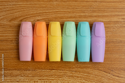 Pastel Highlighters Lined Up on Wooden Desk Background