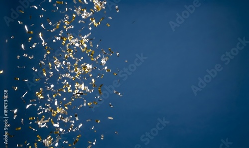 Festive gold and silver confetti falls against a deep blue background, offering a vibrant backdrop for celebrations and events.