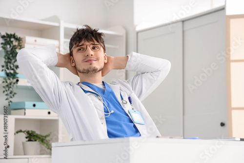 Dreaming male doctor at desk in clinic