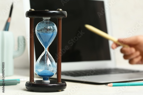 Hourglass near woman workin...