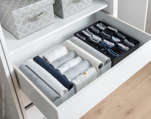 Tableau sur toile Organized White Wardrobe Drawer with Neatly Folded Clothes and Fabric Boxes, Interior Design Concept of Tidiness and Storage Solutions for Clothing Organization in a Modern Home Setting, Wooden Floor