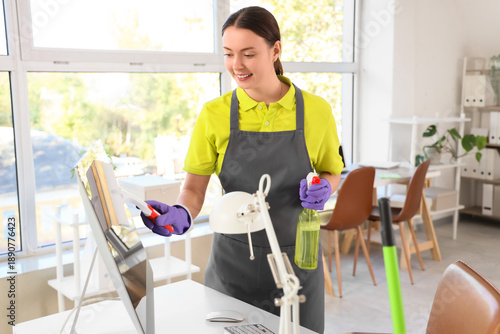 Female janitor cleaning computer monitor in office