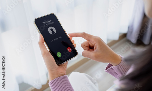 Принти на полотні Woman's hands holding a modern smartphone with an Unknown incoming call notification displayed on the screen