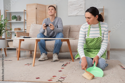 Sad wife sweeping carpet wh...