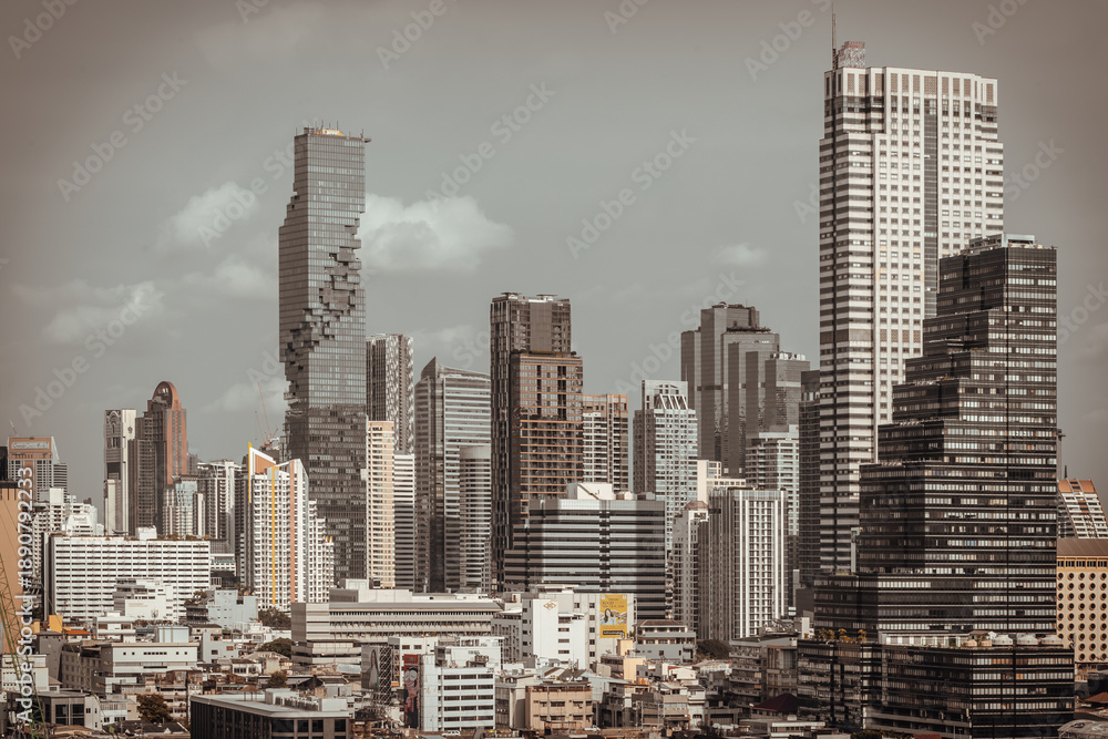 Fototapeta premium Bathed in the muted light of an overcast sky, Bangkok skyline reveals a striking dialogue between sleek modernism and weathered low-rise architecture. At the heart of this contemplative scene, the 'pi