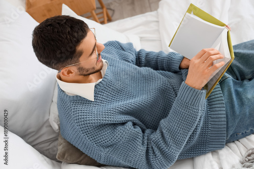 Young man reading book in b...