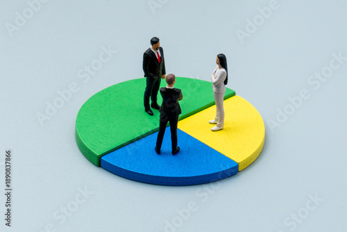 A miniature business figures standing on different colored segments of a pie chart. Shareholders, ownership distribution, corporate investment stakes concept.