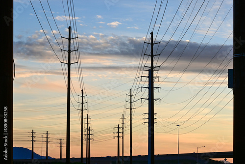 фотографія Power transmission lines and utility poles stretching across landscape at sunset