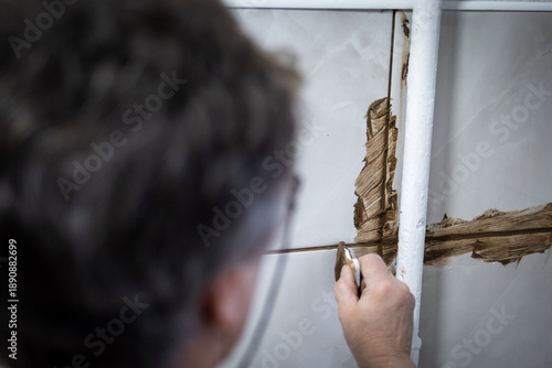 Quadro em tela Worker applies brown grout around a vertical pipe and cross joint on glossy tiles using a small plastic tool