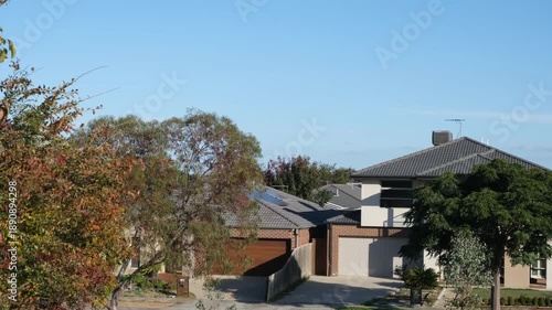 Modern suburban houses surrounded by trees in Australia. A quiet residential neighborhood with detached family homes. Suburban living scene in an established housing estate in Australia.