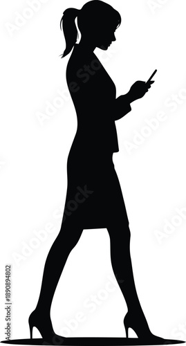 Full body silhouette of a woman in business attire walking and looking at her mobile phone