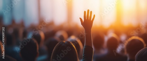 Audience member raising hand during presentation at conference or seminar with sunlight and blurred background for business and education concepts