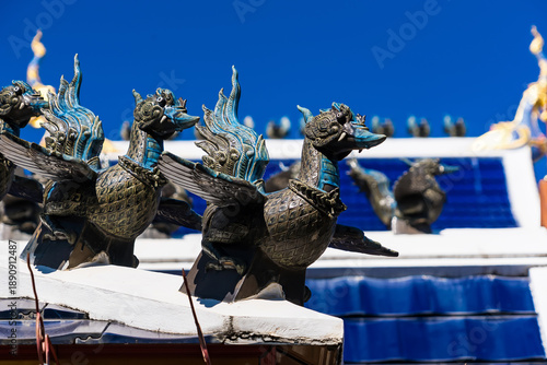 Bilde på lerret Symbolic Crests on Roof: Intricate, mythical bird sculptures adorn a temple roof against a clear blue sky, demonstrating architectural craftsmanship and cultural symbolism