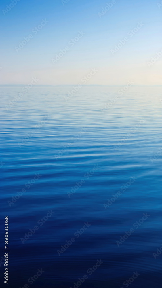 Obraz premium Calm ocean with gentle ripples under a clear sky.