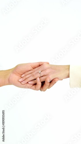 Two people gently hold hands wearing engagement rings against a plain white background. This minimalist scene symbolizes love, trust, and commitment—ideal for evergreen romance or Valentines themes.