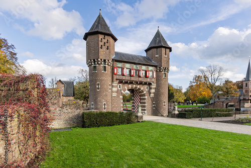 Fotografie A monumental brick gatehouse with twin towers and a drawbridge at the entrance of De Haar Castle park in the Netherlands under a blue sky