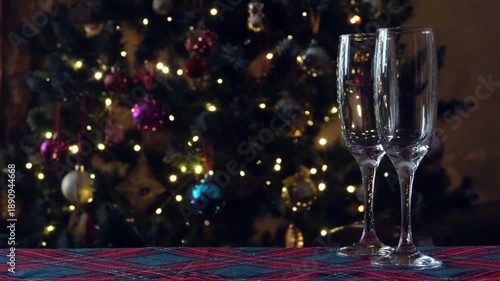 Two champagne flutes on festive table with Christmas lights