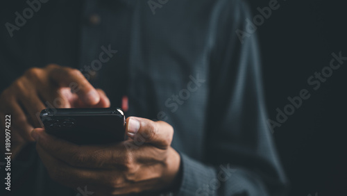 Bild auf Leinwand Close-up of hands holding a black smartphone, the background is blurred, the person is wearing a blue shirt
