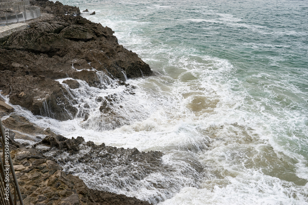 Fototapeta premium Waves crashing against rocky shoreline in Santander.. Santander, Spain