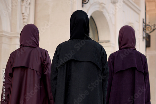 Qatar, Doha, 17.10.2022: Close-up rear view of three women in dark abayas.