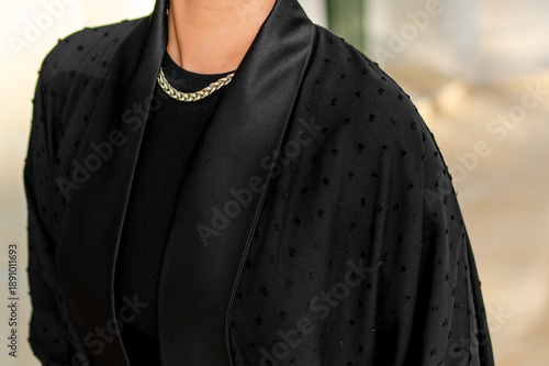 Qatar, Doha, 17.10.2022: Close-up of a black abaya and a gold chain in soft natural light.