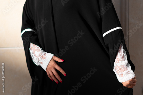 Qatar, Doha, 17.10.2022: Black abaya with lace cuffs and elegant hand gesture in soft natural light.