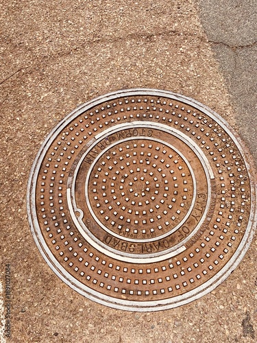 A metal storm drain cover in the pavement of a street in Carlsbad, California.