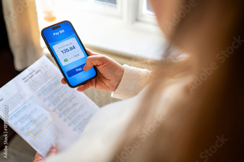 Checking utility bills on smartphone at home. Household expenses and budgeting concept.