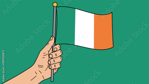 Human hand firmly holding a small Irish tricolor flag against a solid green background for Saint Patricks Day celebrations.