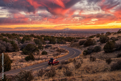 Red Car Driving Into A Vibrant Albuquerque Sunset