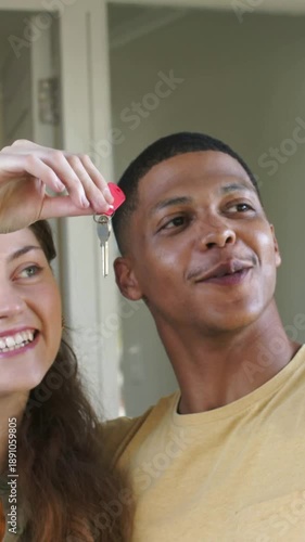 Vertical video: Arriving home, woman wearing smartwatch raising red key fob, showing partner keys