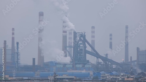 Steel plant and factory chimneys releasing smoke under heavy smog conditions in winter, showing industrial air pollution and low visibility, environmental impact and emissions in Liuzhou, China.