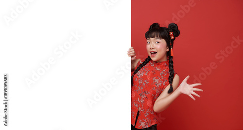 Tableau sur toile Asian child presenting blank banner for Chinese New Year promotion young girl peeking and gesturing with excitement to showcase copy space festive marketing holiday celebration tradition and joy