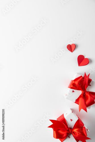 Gift box, present decorated with red ribbon bow and hearts, red heart decoration on white background. Valentine's day, February 14, birthday, 8 march women's day gift, surprise. Love and romance.