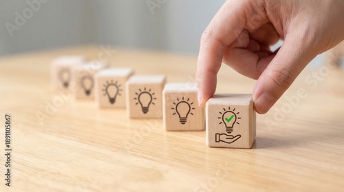 Human hand selecting a wooden block with a lightbulb checkmark symbolizing a successful new idea on a bright wooden table
