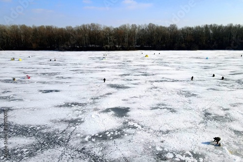 icy background in winter. Fishermen are fishing on beautiful blue ice, frozen river, lake in winter