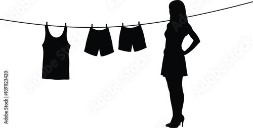 Silhouette of a woman standing next to a clothesline with black tank and shorts hanging