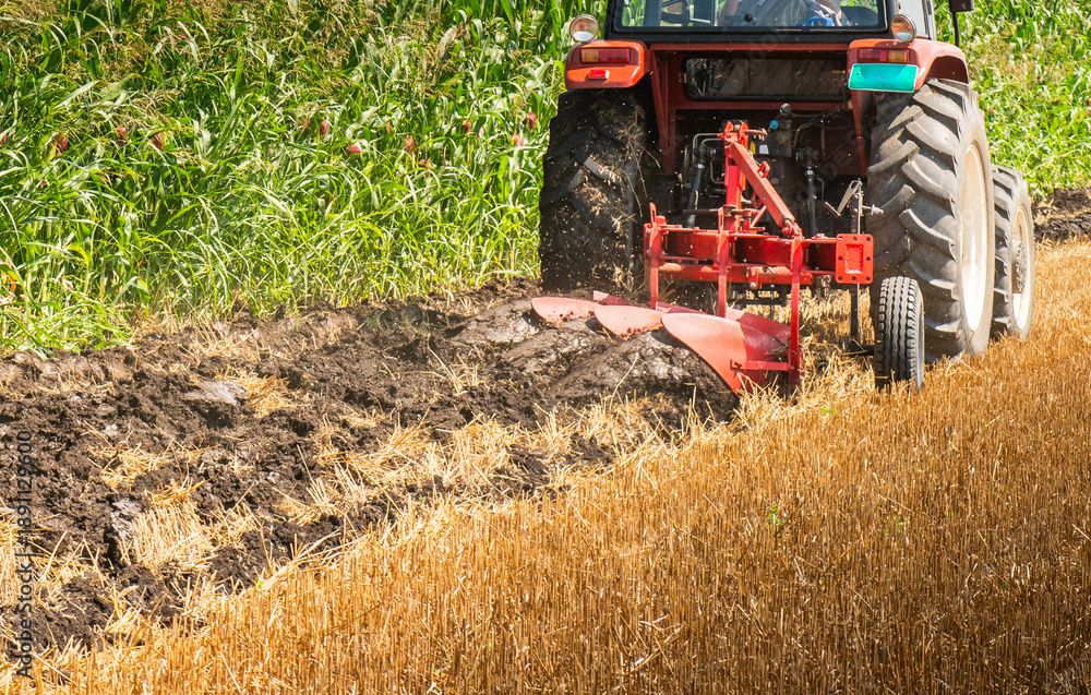 Obraz premium Agricultural works at farmlands, agriculture tractor-closeup