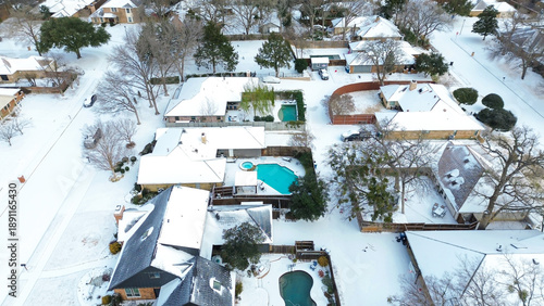 Backyards along MacArthur Boulevard during Winter Storm Fern display snow covered patios, muted lawns, partially frozen pools. Bare trees, softened roof textures shape frosted scene, Coppell, TX
