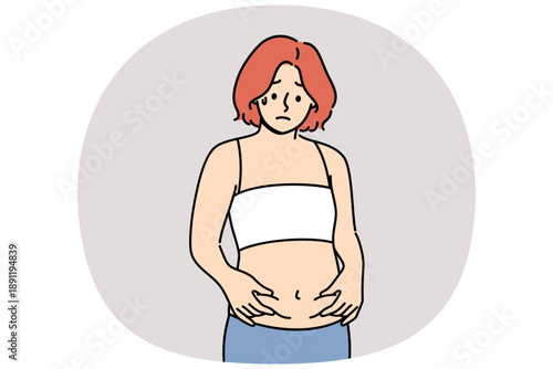 Woman is frightened by appearance of belly fat and afraid of gaining excess weight after changing diet. Thin girl thinks she has become fat, suffering from psychological problems and low self-esteem