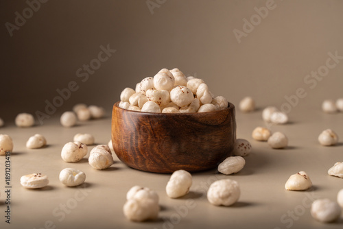Phool Makhana, Fox Nut, Lotus Pops Seeds, Gorgon nut, Euryale Ferox on a wooden bowl with beige background.