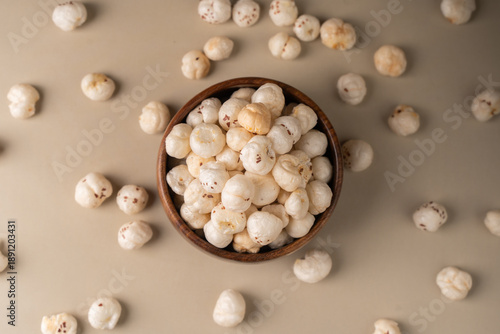 Phool Makhana, Fox Nut, Lotus Pops Seeds, Gorgon nut, Euryale Ferox on a wooden bowl with beige background. © sdx15