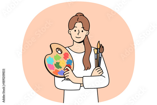 Woman artist holds brushes for painting and palette for mixing watercolor paints. Portrait of beautiful artist girl who is interested in creative hobby and wants to exhibit in art gallery